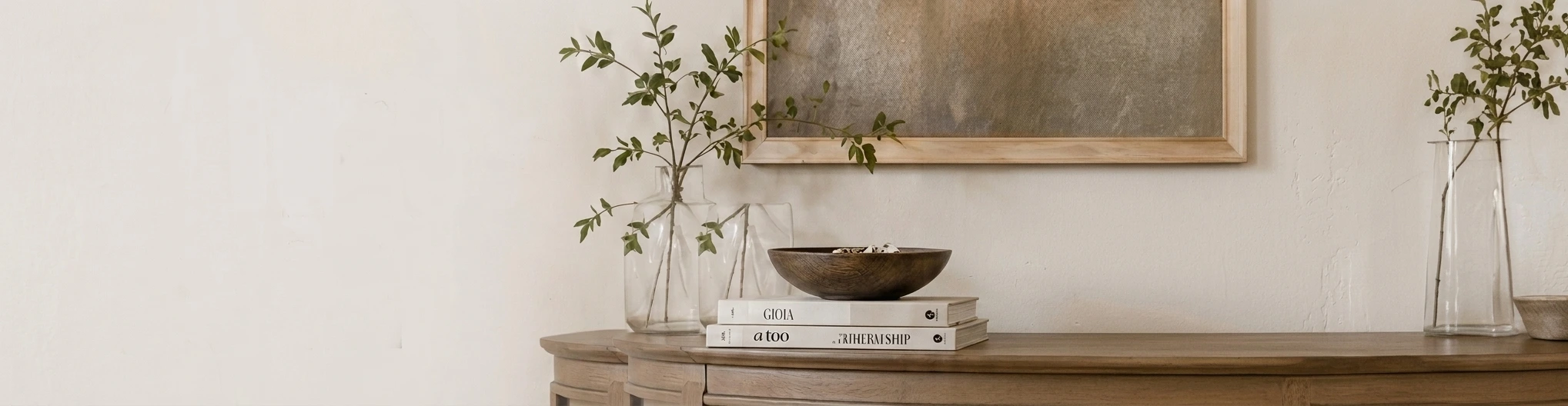 Console table styled with a wooden bowl, books and olive branches